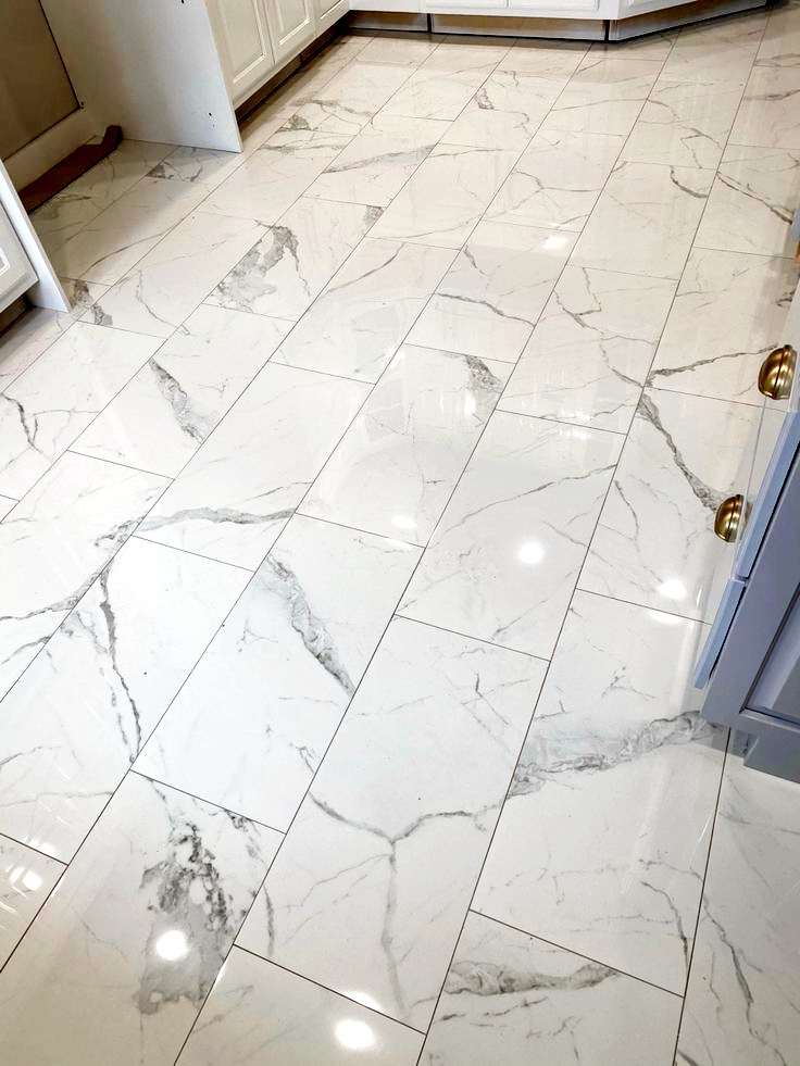 Marble floor tile installation with herringbone chevron pattern showing precision grout lines and luxury finish