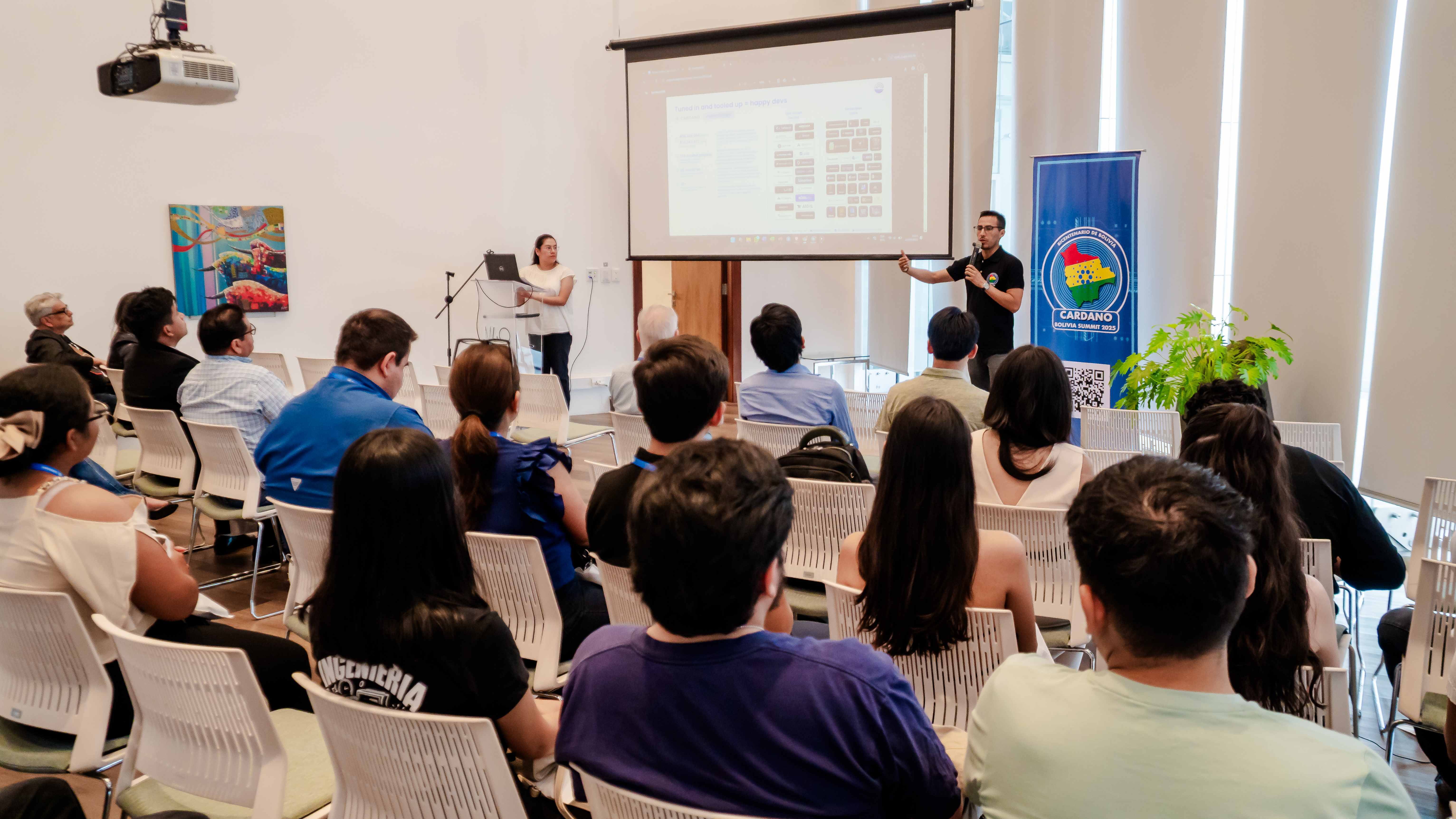Sergio presenting at Cardano Bolivia Summit with audience and banner visible