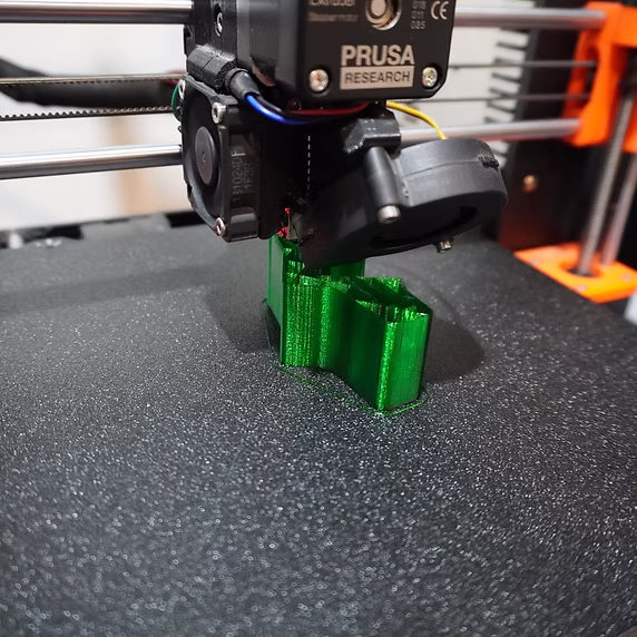 A Prusa printer running, the extruder laying down filament on a part mid-print