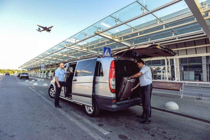 Drivers loading luggage at airport terminal with plane taking off