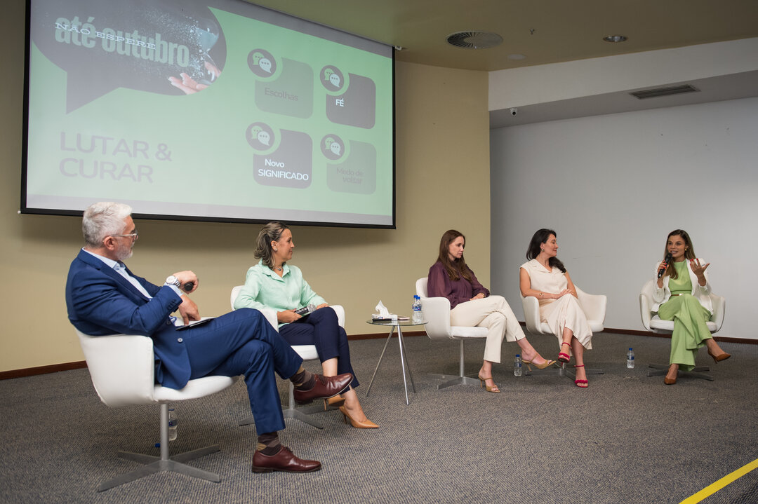 Painel com 5 pessoas, slide LUTAR & CURAR ao fundo