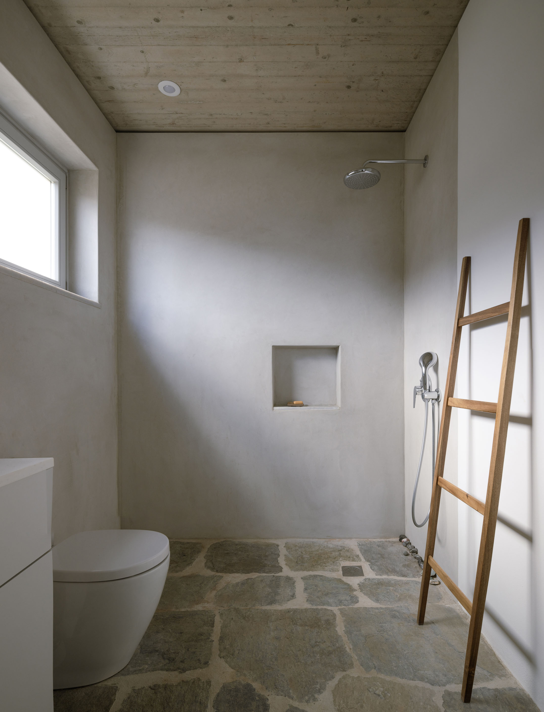 Minimalist bathroom with stone floor and concrete ceiling