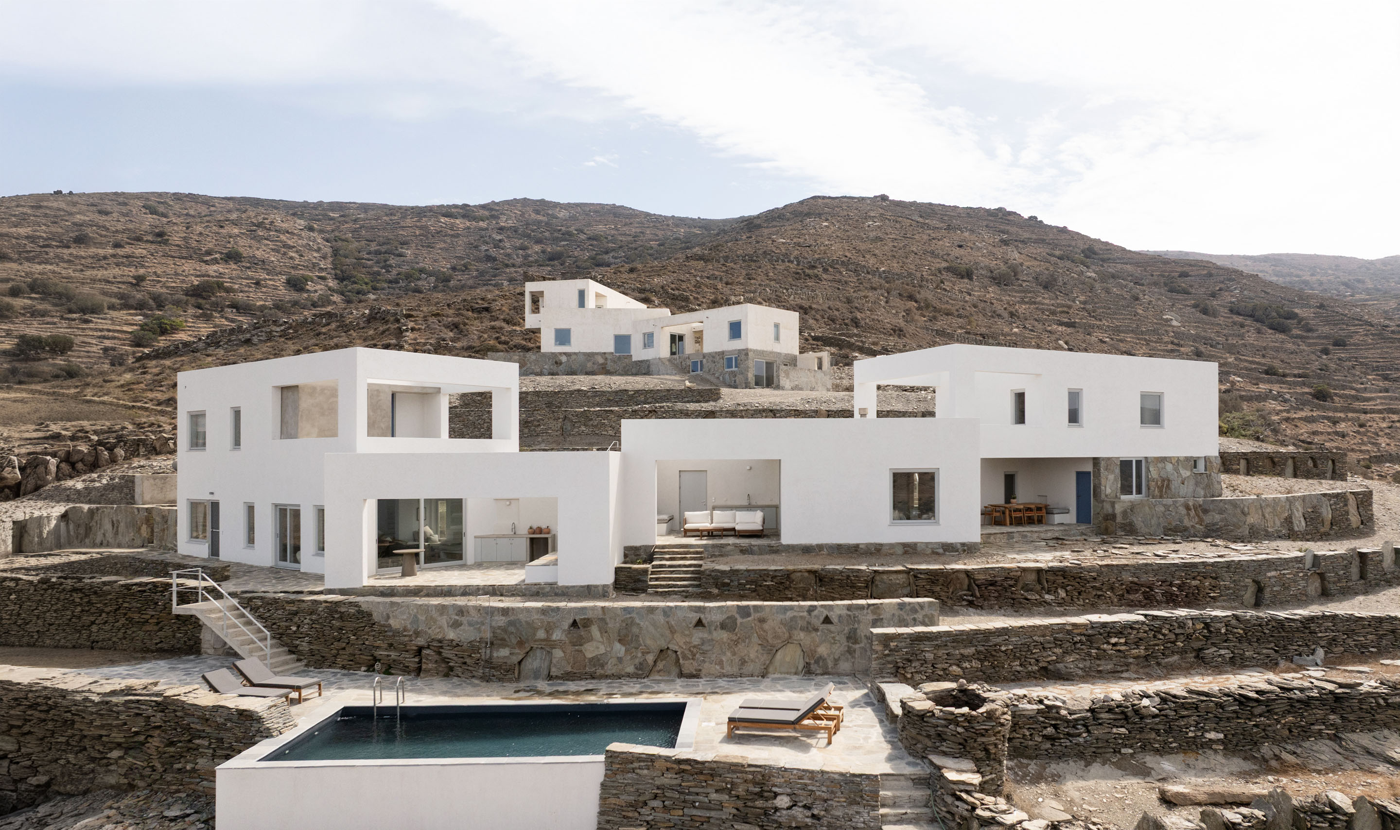 Main exterior view of Korthi Houses with pool and terraced stone walls