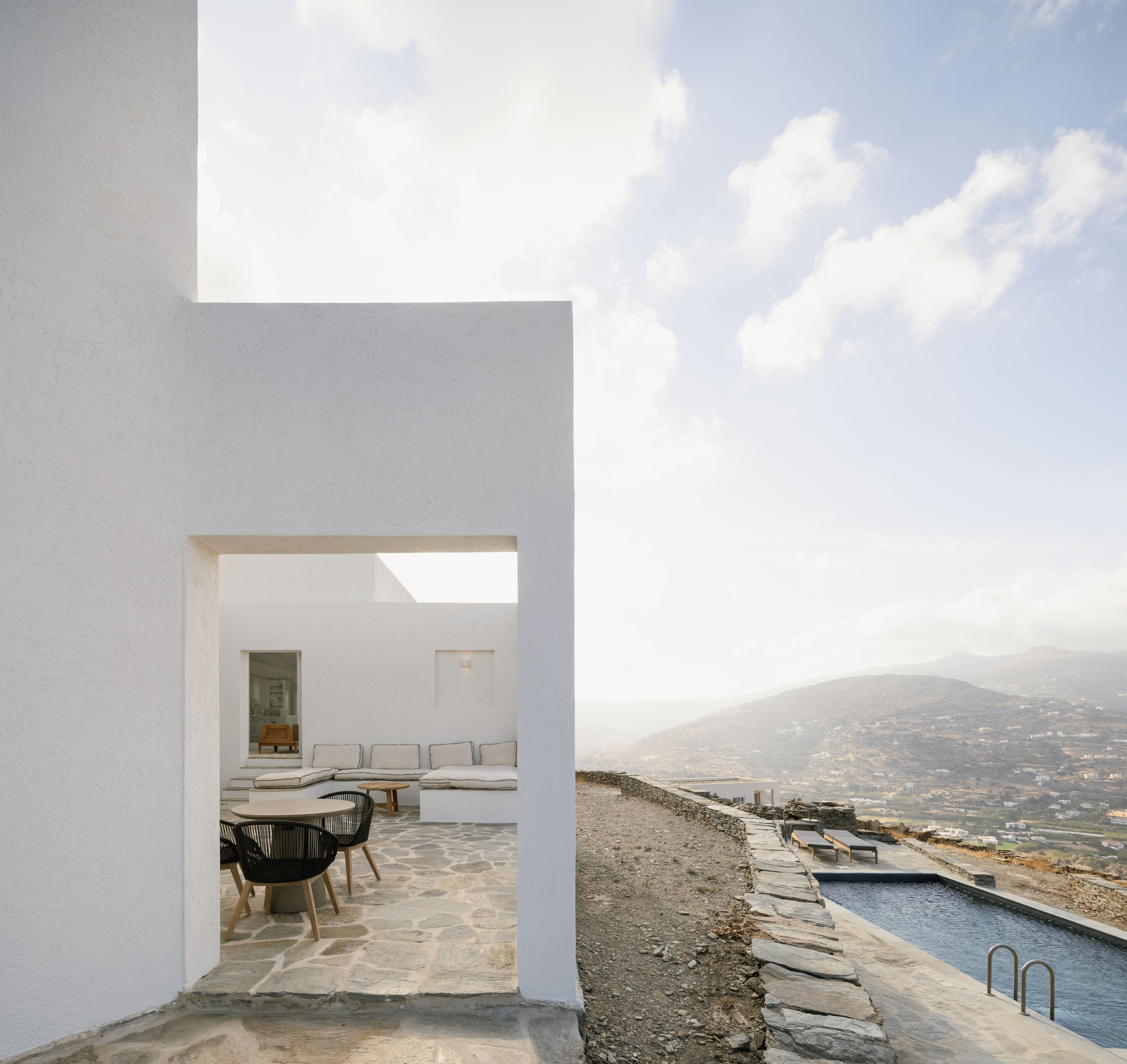 Whitewashed passage framing terrace seating and the pool above the valley