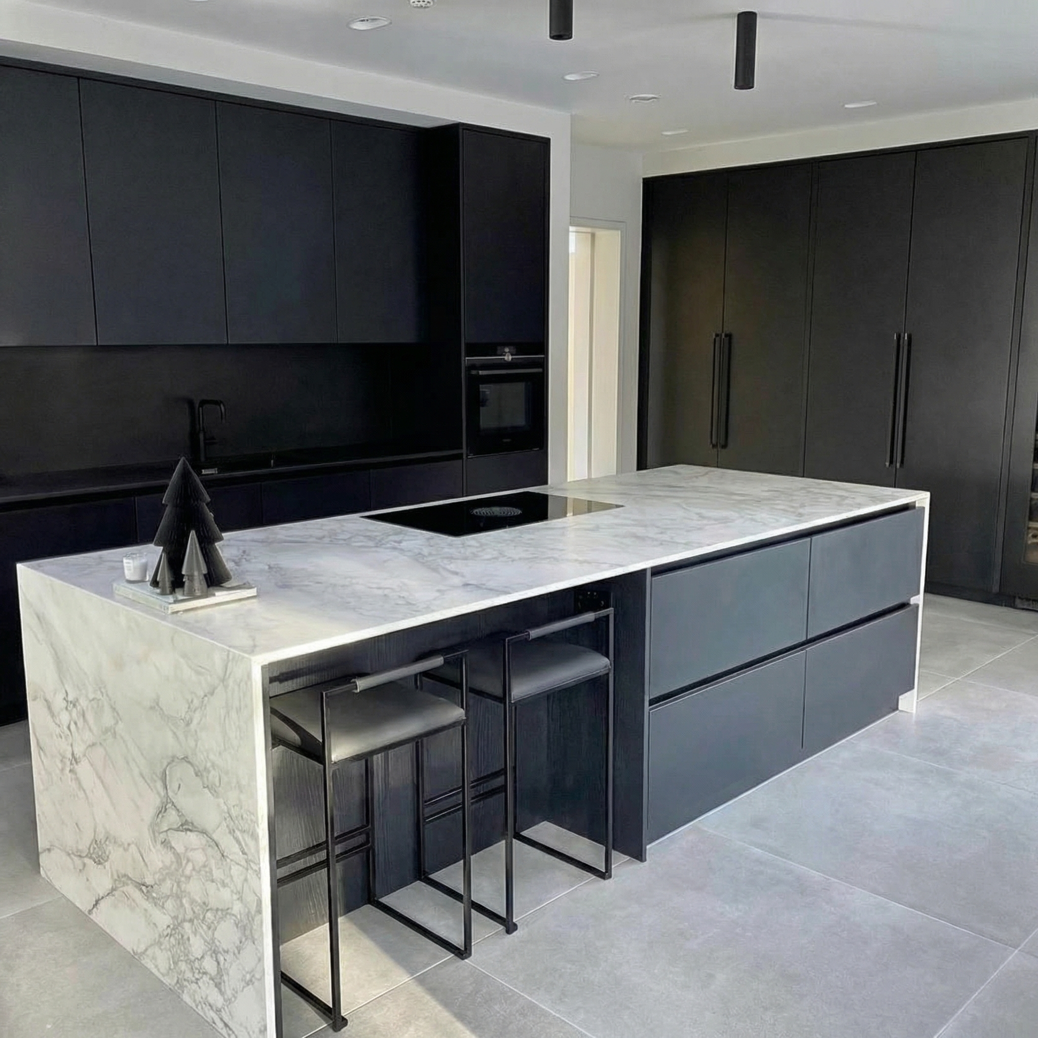 Cuisine contemporaine noir mat avec ilot central en marbre blanc veine, finition waterfall — projet sur mesure MARBELLO