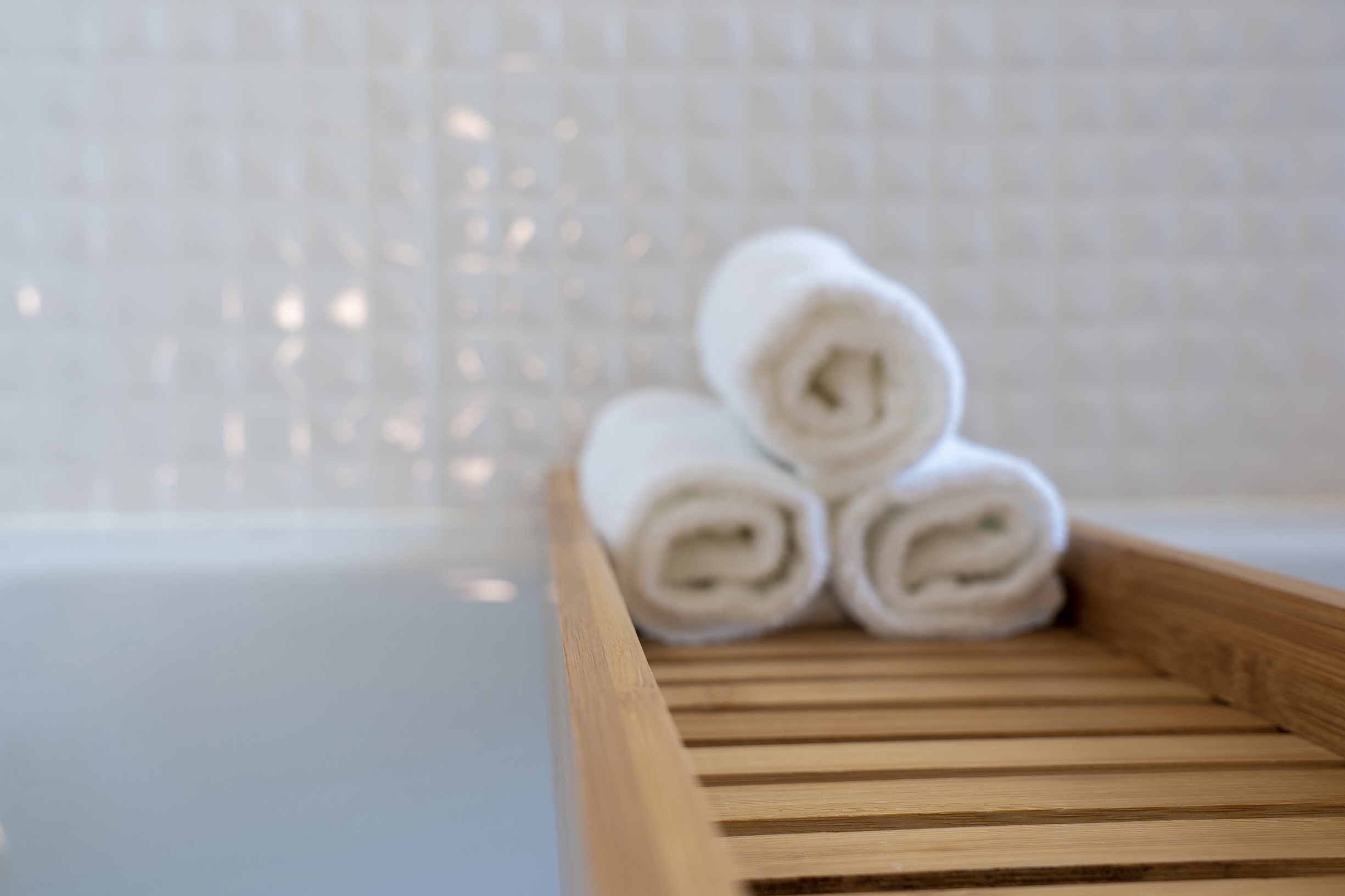 Luxury spa amenities with rolled towels on wooden shelf