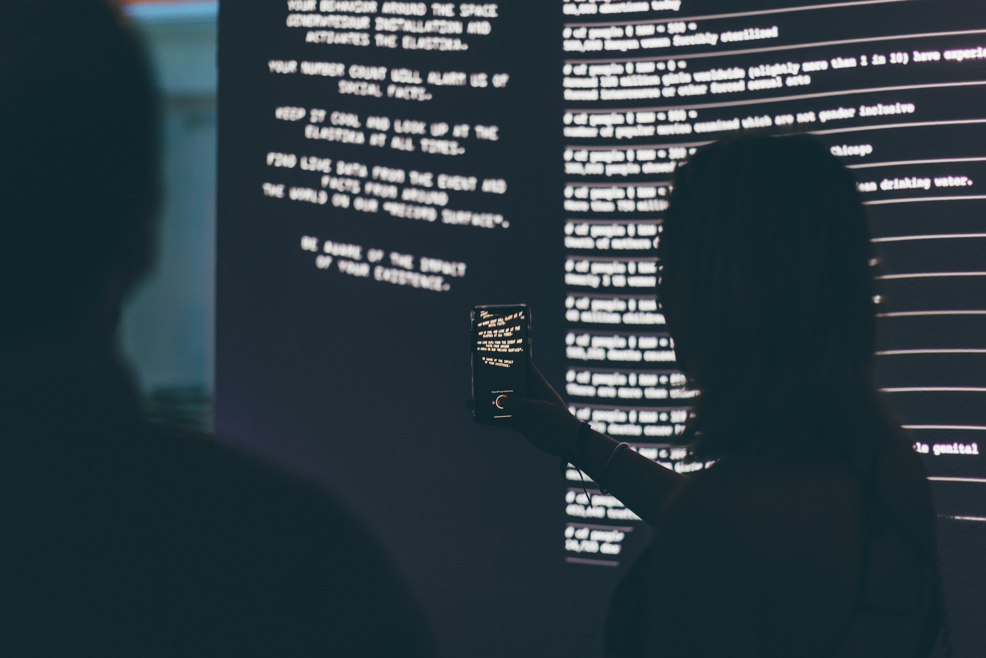 Visitors viewing projected text and statistics about women's rights as part of the Rote installation's data display component
