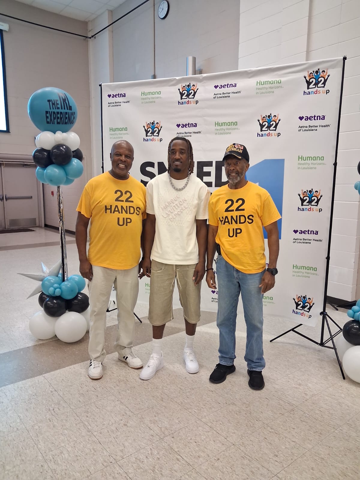 L'Jarius Sneed posing with community elders and a veteran wearing 22 Hands Up shirts