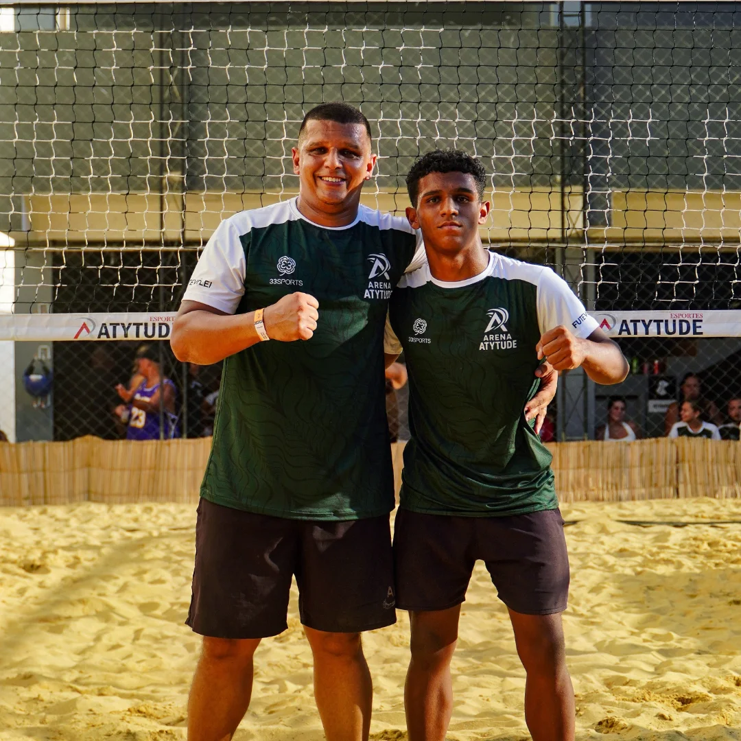 Dupla de atletas posando na areia em uniforme verde da Arena Atytude com logo 33Sports