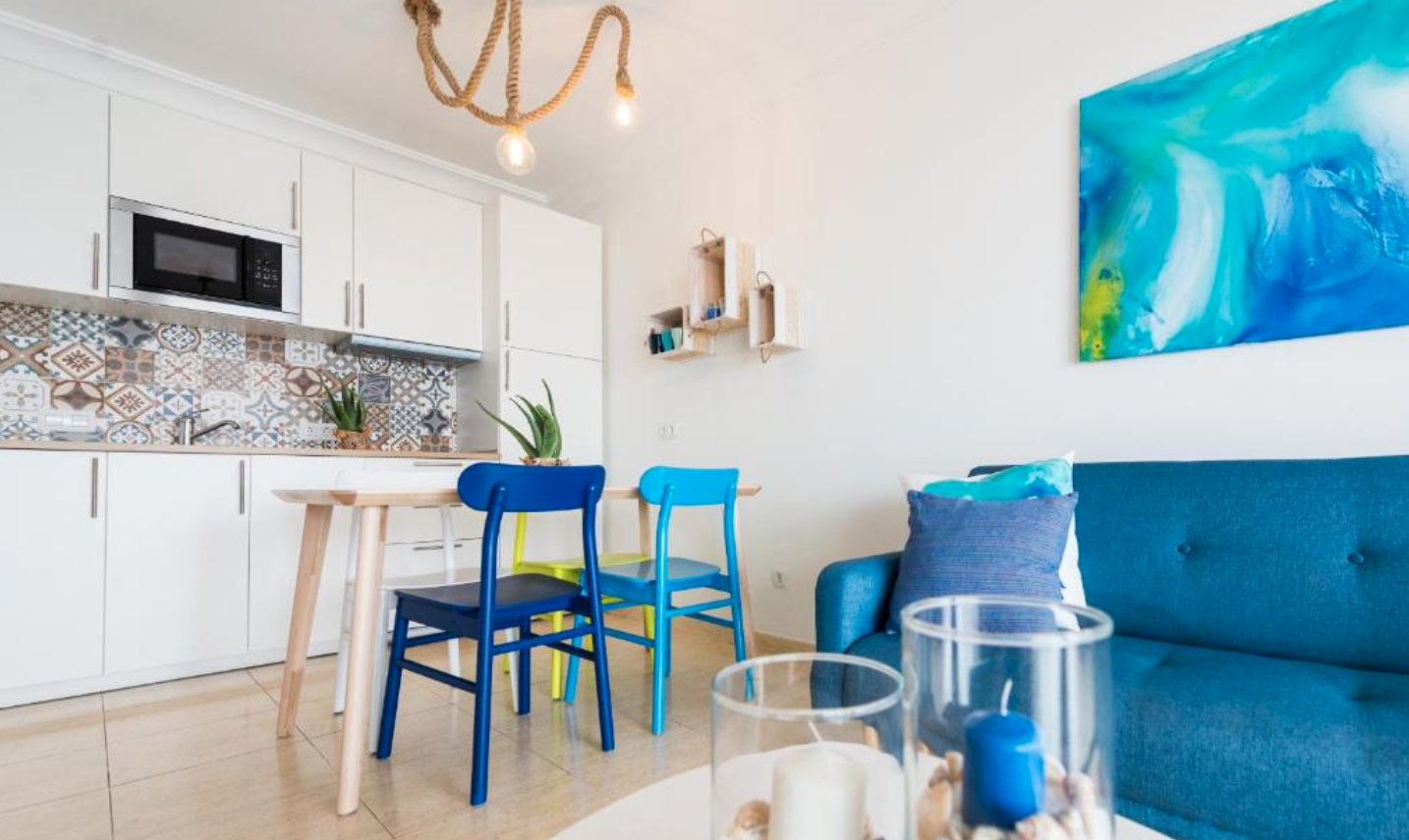 Kitchen and dining area with colourful chairs, blue ocean artwork on the wall