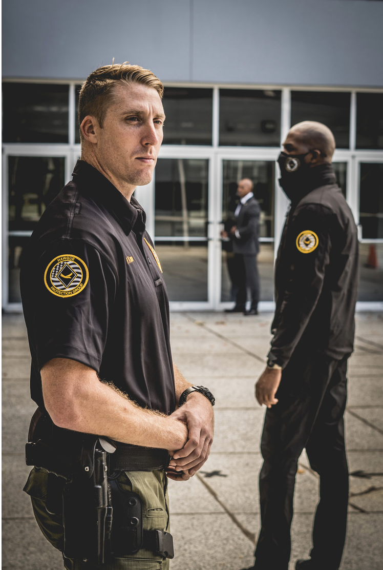Two uniformed Hawque security officers maintaining a professional presence outside a commercial property entrance.