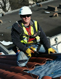 Kurt Kettering in safety gear smiling while working on a roof