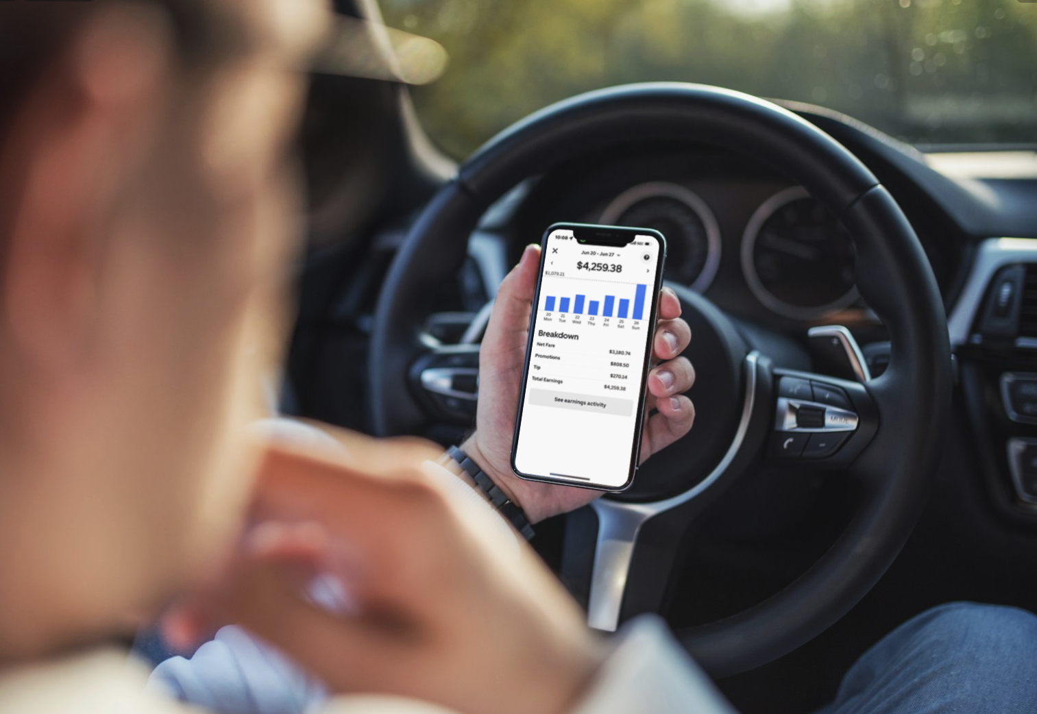 Driver checking earnings of $4,259.38 on smartphone while in car