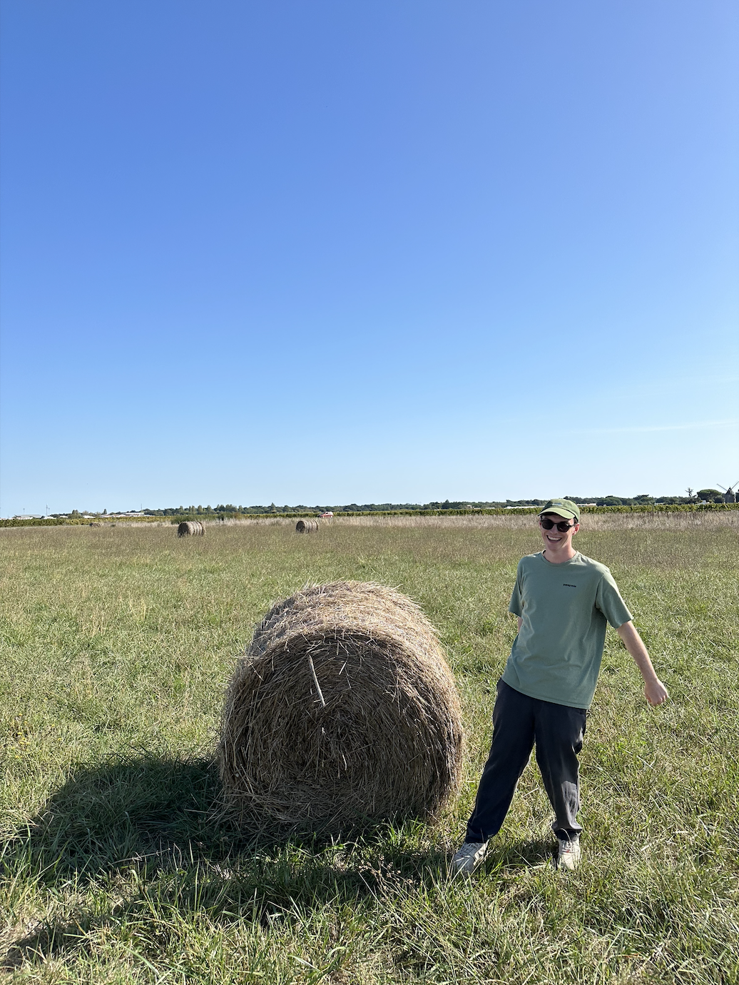 Will Hofbauer standing next to a hay bale in a sunny field