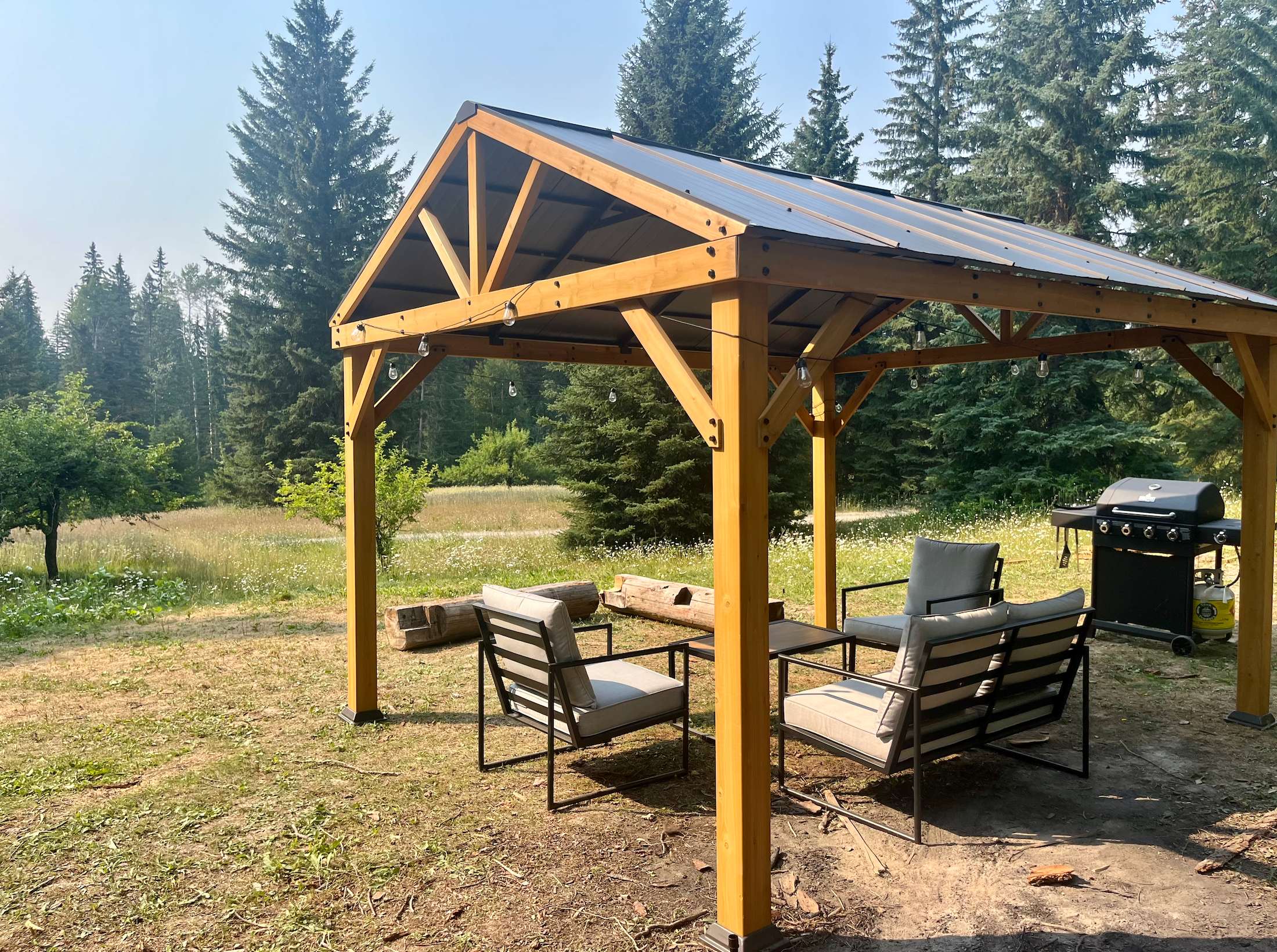Glamping gazebo area with seating and BBQ