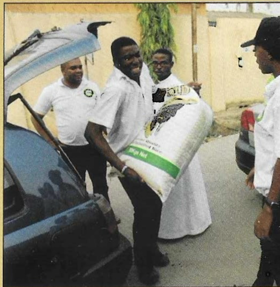 A volunteer carries a bag of rice for distribution to the elderly