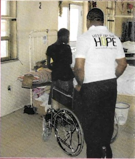 Keep Up The Hope volunteer wheeling patient through ward