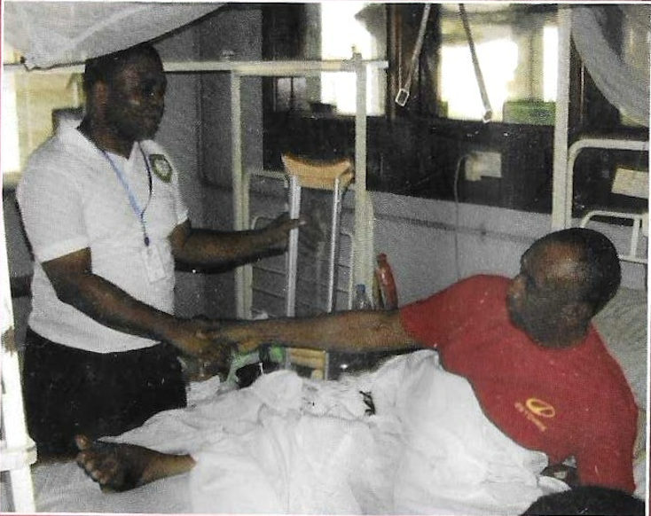 Volunteer greeting patient in red shirt at bedside