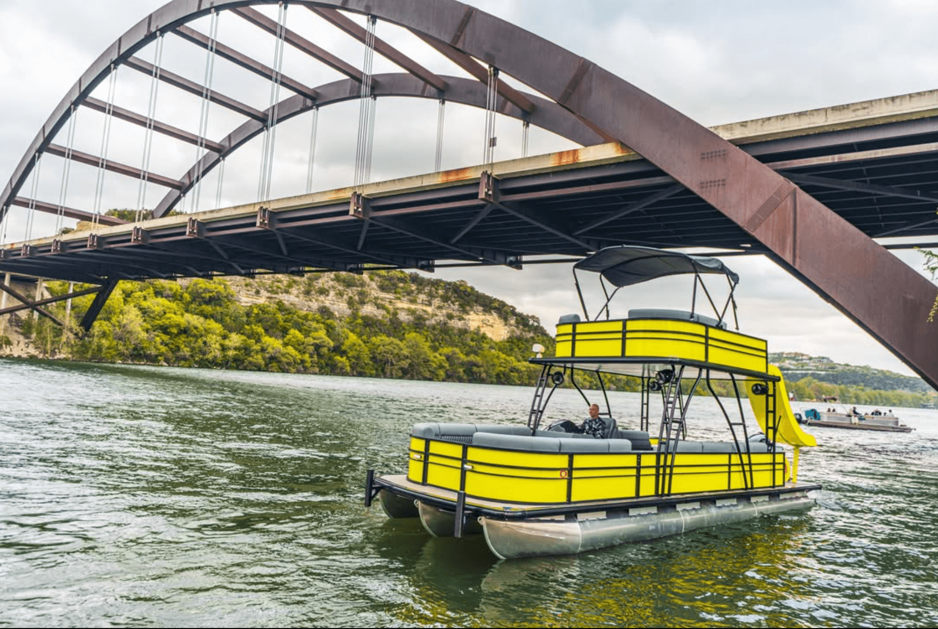 Yellow double-decker party barge under Pennybacker Bridge on Lake Austin