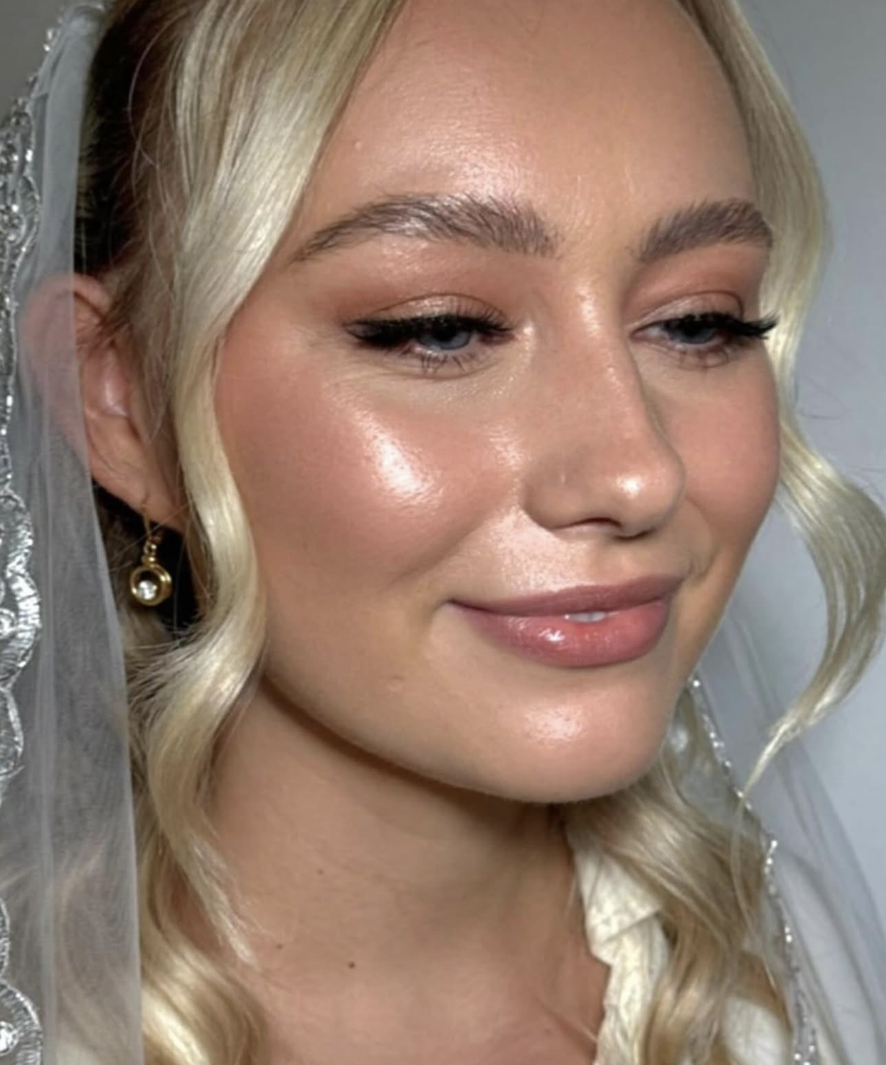 Bride with glowing dewy skin, soft bronzed glam and a lace veil