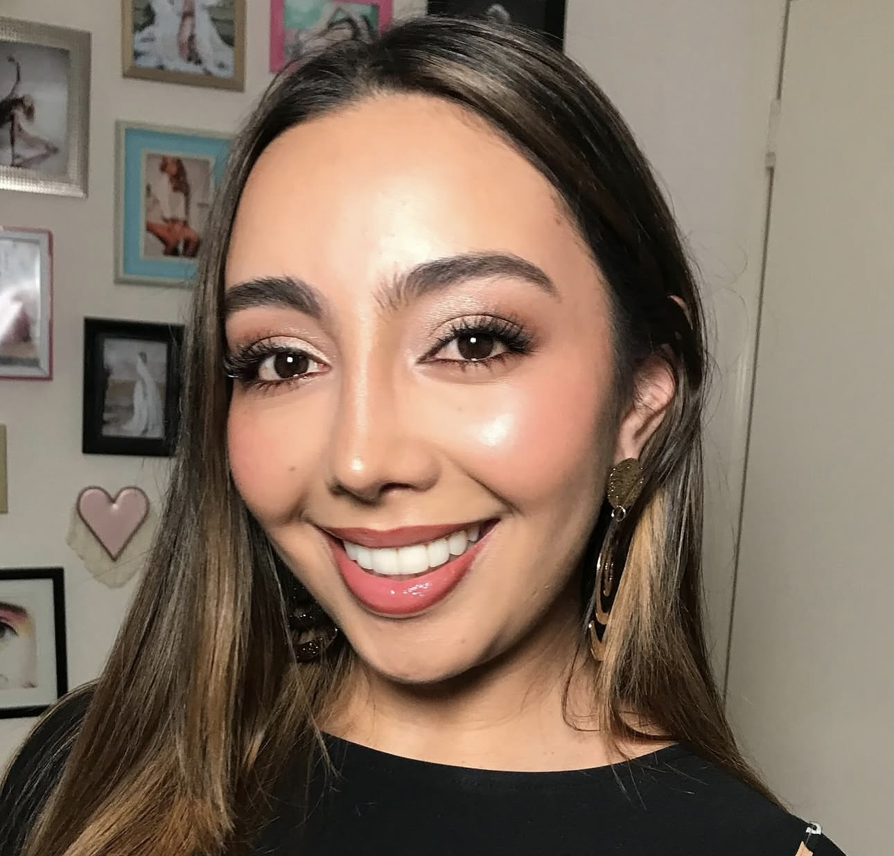 Brunette client smiling with soft glam and gold earrings