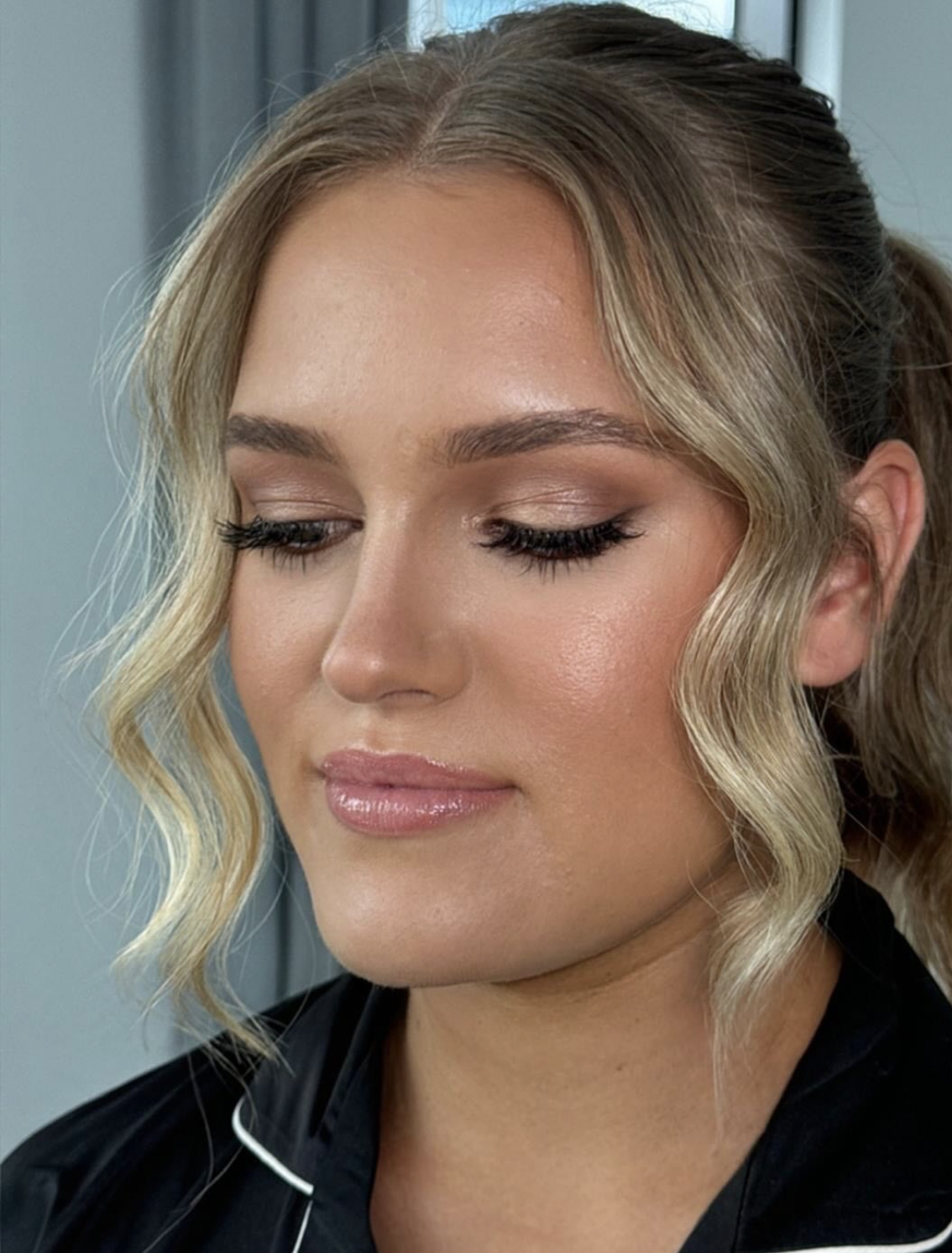 Blonde client with soft neutral glam, glossy nude lip and soft waves