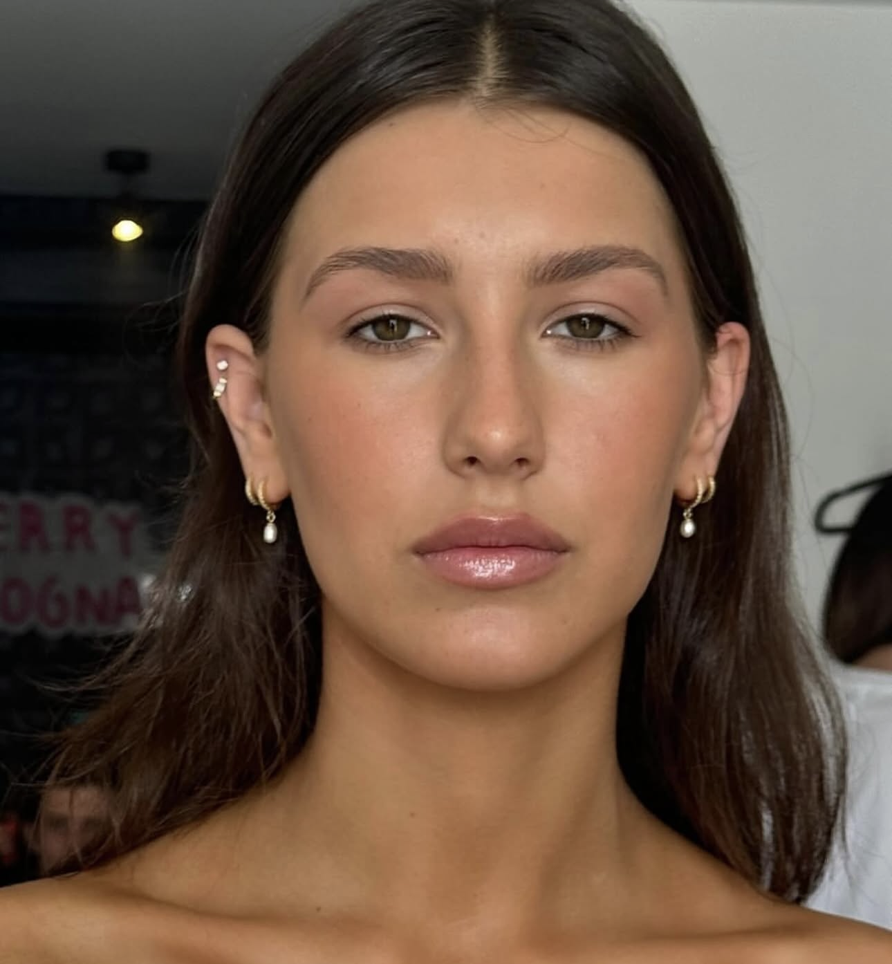 Client with soft natural glam, glossy lip and pearl earrings