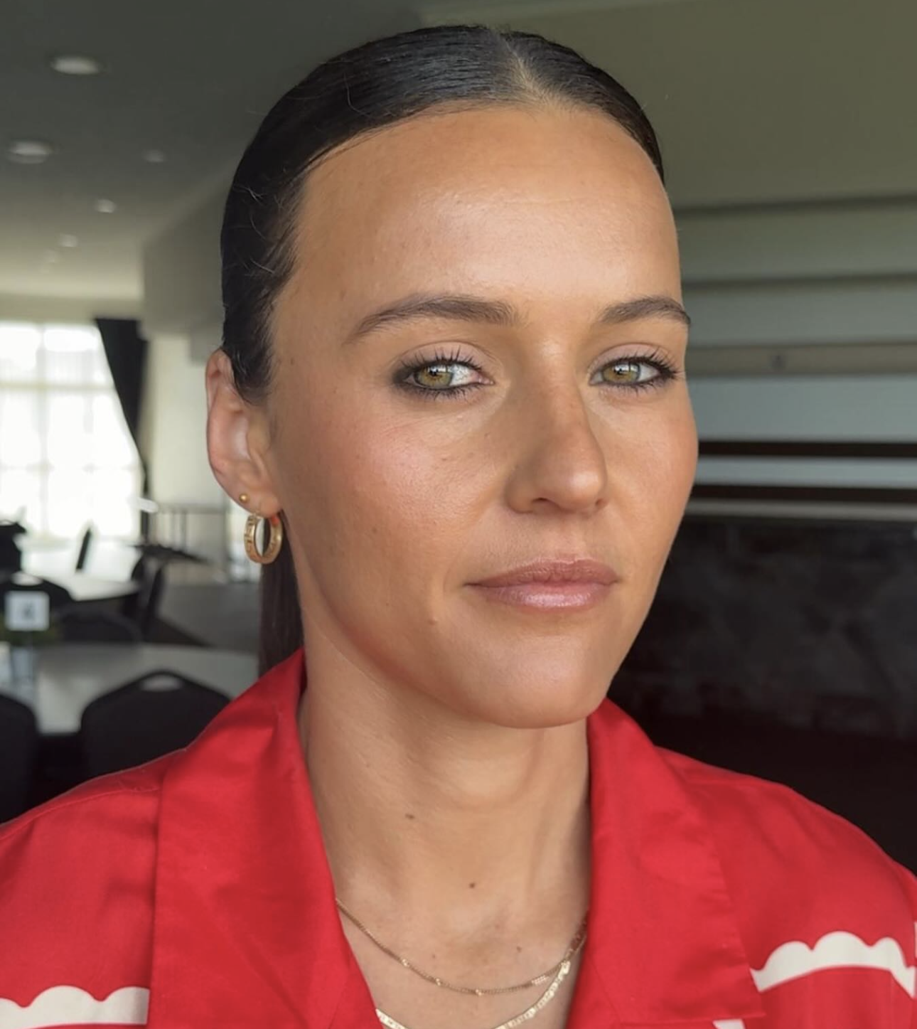 Client with sleek slicked-back hair and natural bronzed glam in a red shirt