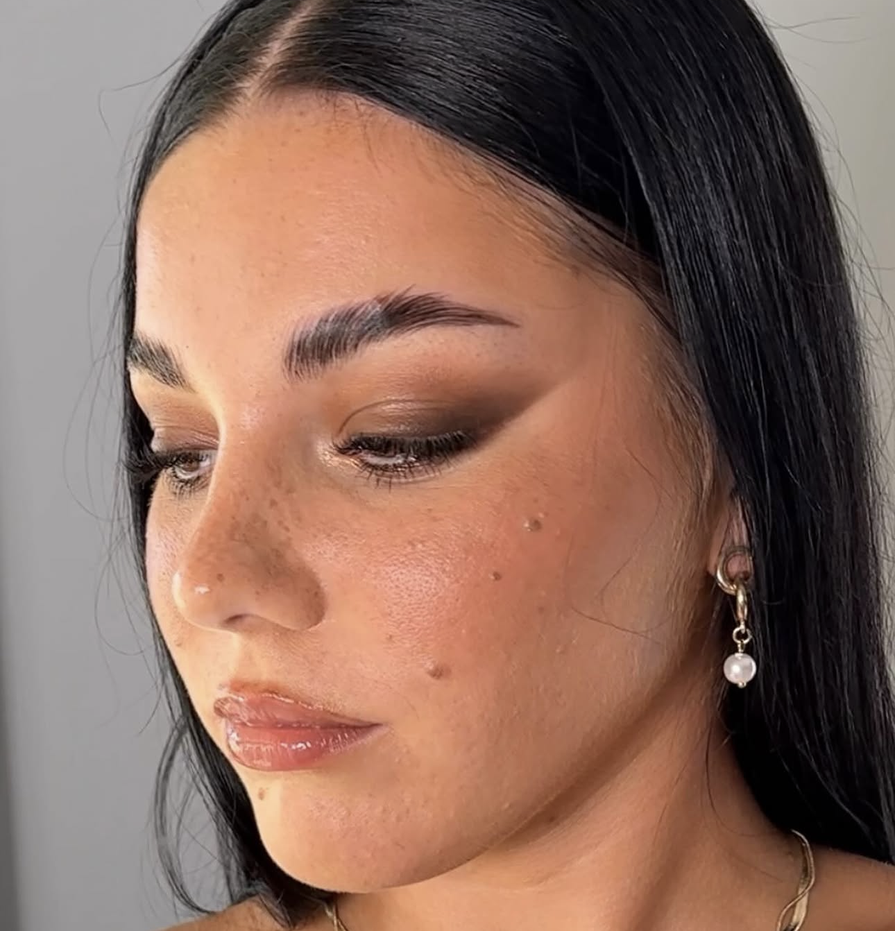 Dark-haired client with bronze smokey eyes, freckles and a glossy lip