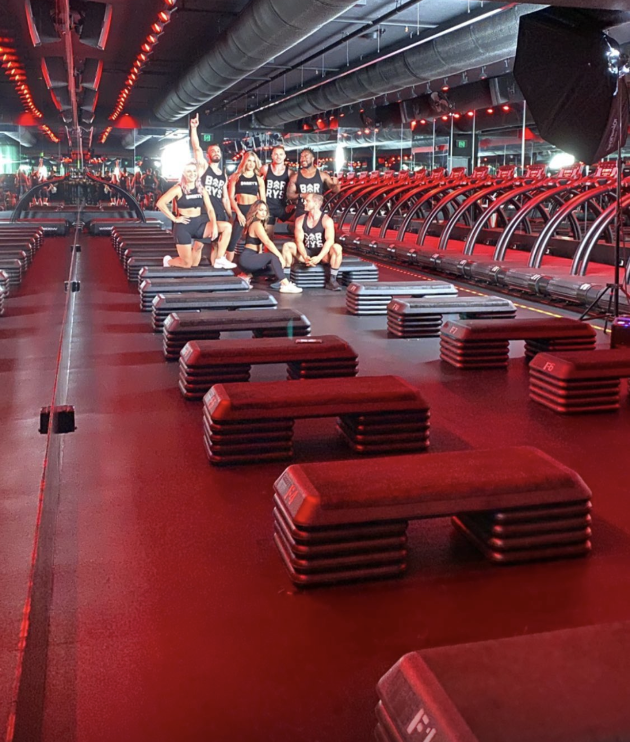 Fitness brand shoot with a team on set in a red-lit gym studio