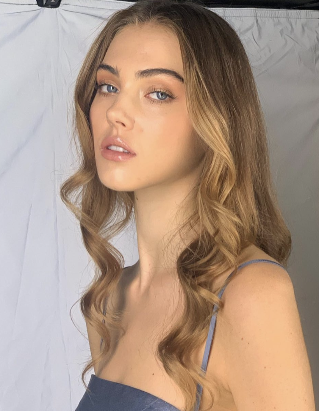 Soft glam look with curled hair on a grey backdrop