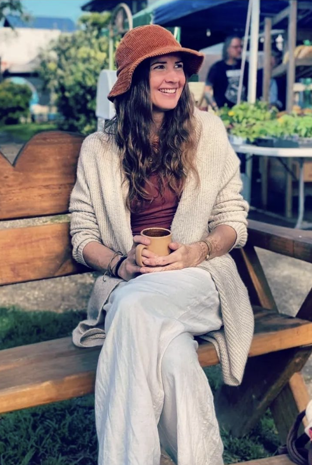 Julie Faulkner smiling warmly at a farmers market, holding a mug