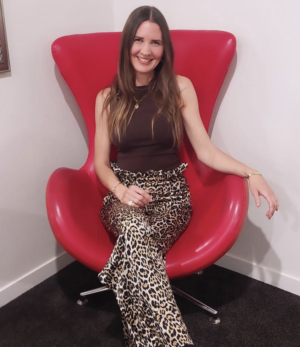 Julie Faulkner smiling, seated in a red egg chair