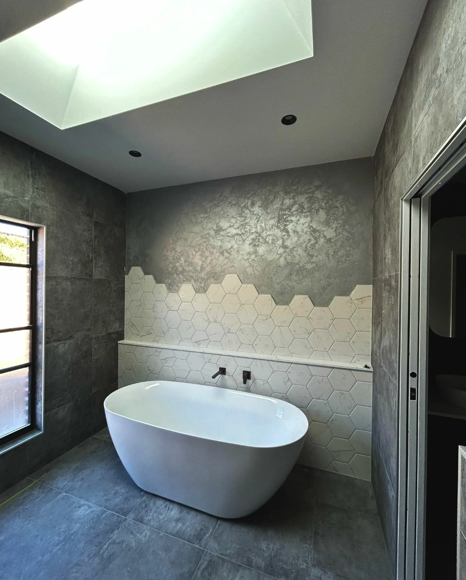 Concrete bathroom with hexagonal marble feature wall and freestanding tub