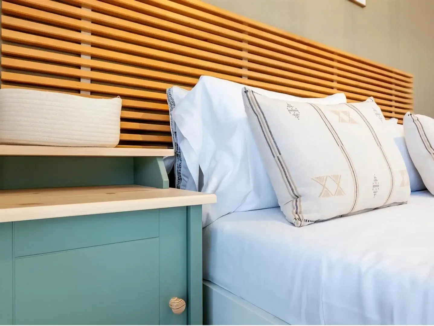Bedroom detail with teal nightstand and decorative pillows