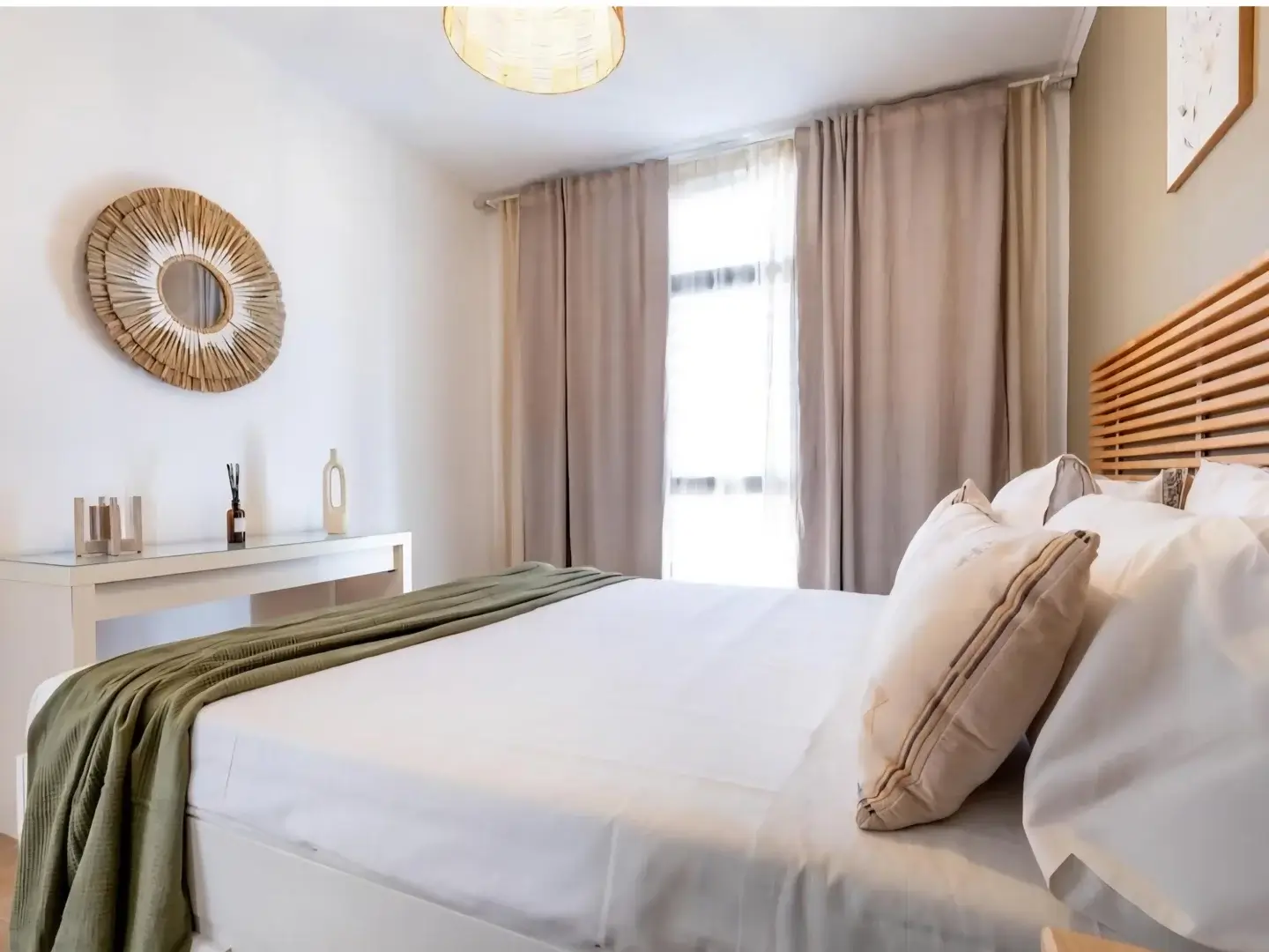 Master bedroom with rattan mirror and green throw