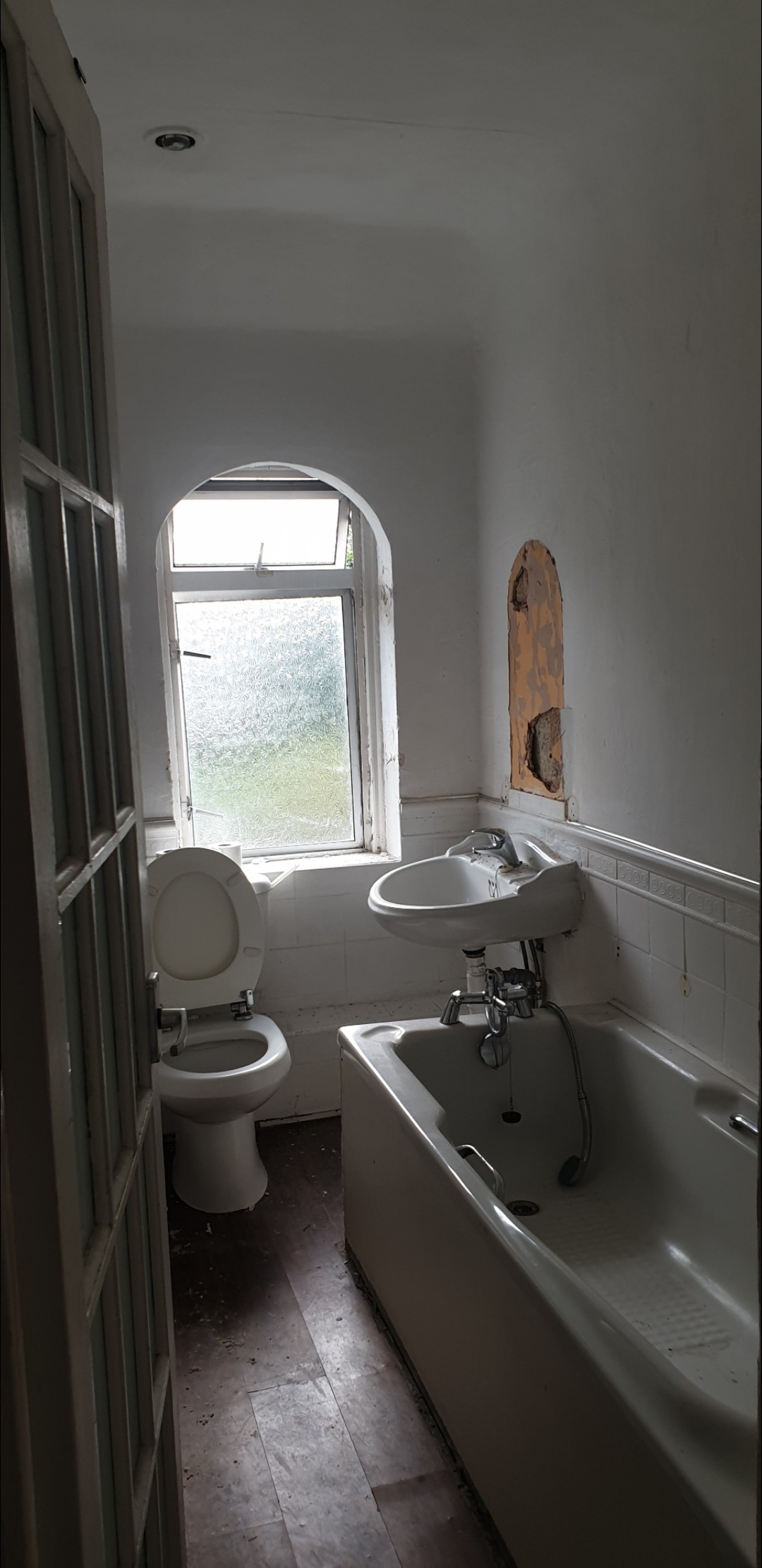 Bathroom before renovation - damaged walls and old fixtures