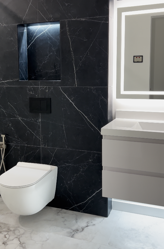 Black Nero Marquina marble wall with wall-hung toilet, illuminated niche and white Calacatta marble floor