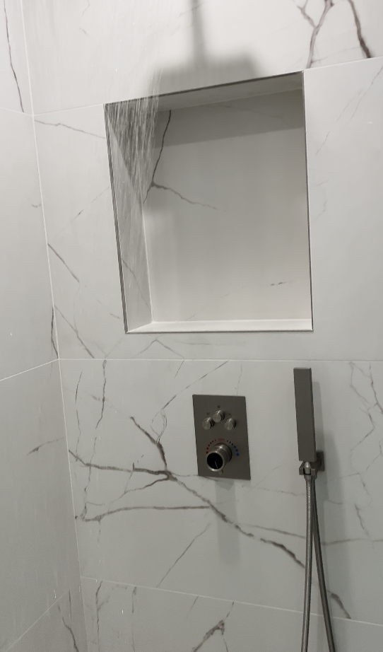 White Calacatta marble shower with flush stainless recessed niche and thermostatic valve