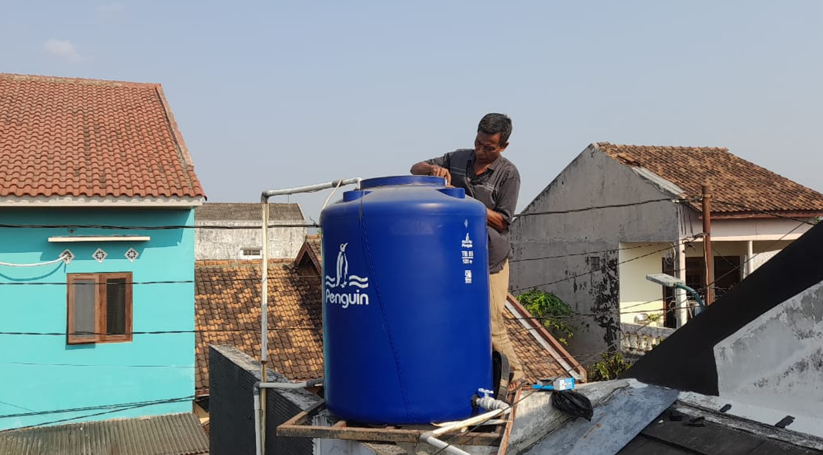Teknisi Muara Pompa sedang memasang tandon air