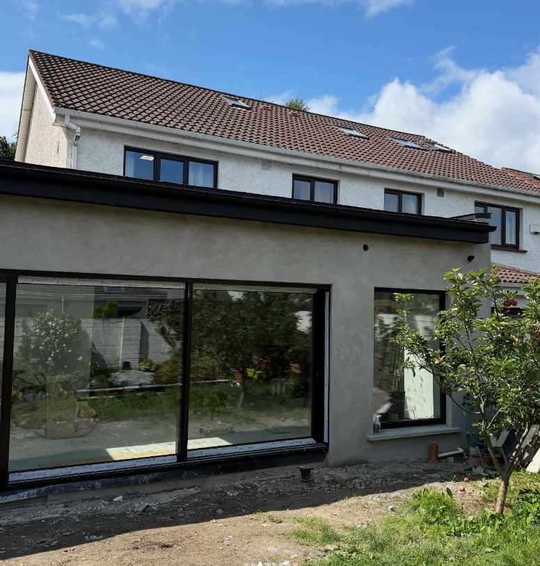 Rendered single-storey extension with full-width sliding doors (in progress) in In progress
