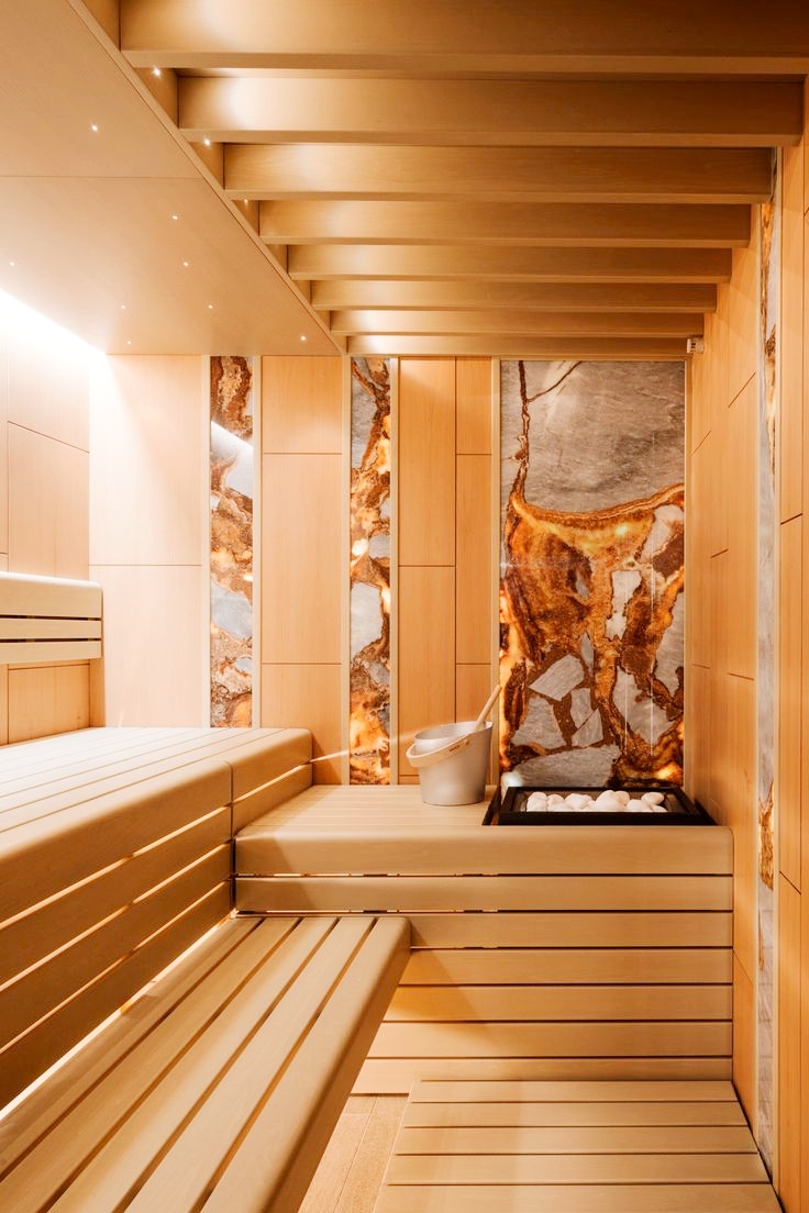 High-end sauna room with cedar wood construction, heated bench seating, and ornate stone accent wall