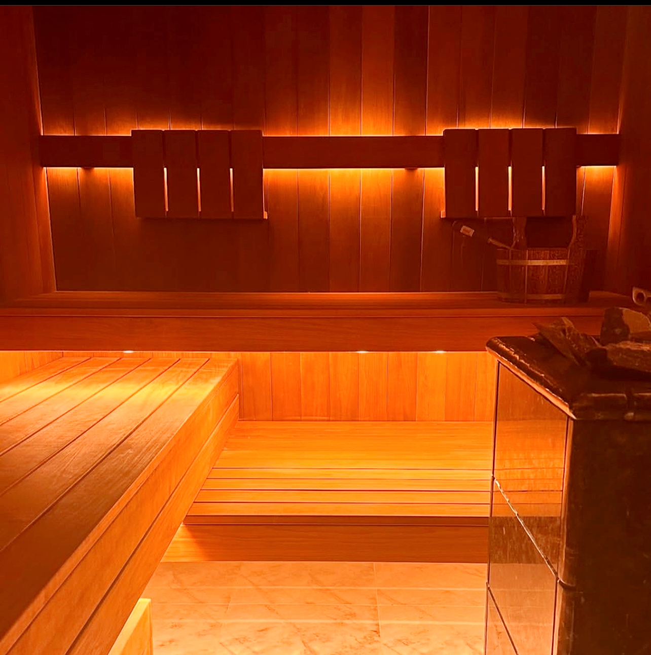Professional sauna interior with dramatic backlighting creating warm amber glow and therapeutic atmosphere