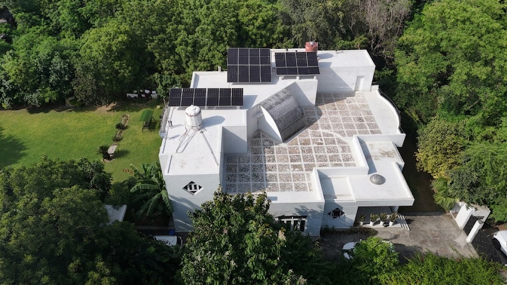 Aerial view of a modern white villa with a rooftop solar array