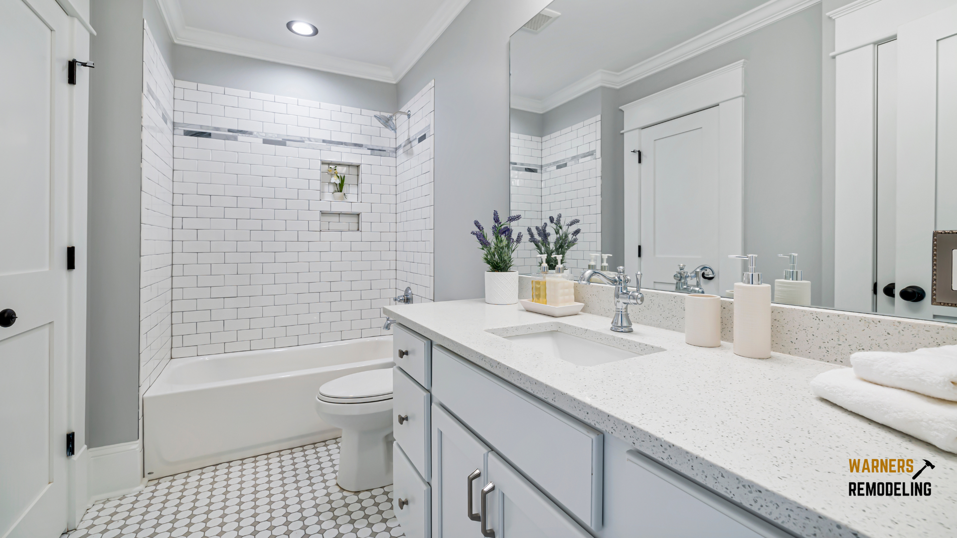 Bright remodeled bathroom with white subway tile tub surround, quartz vanity countertop, and large mirror