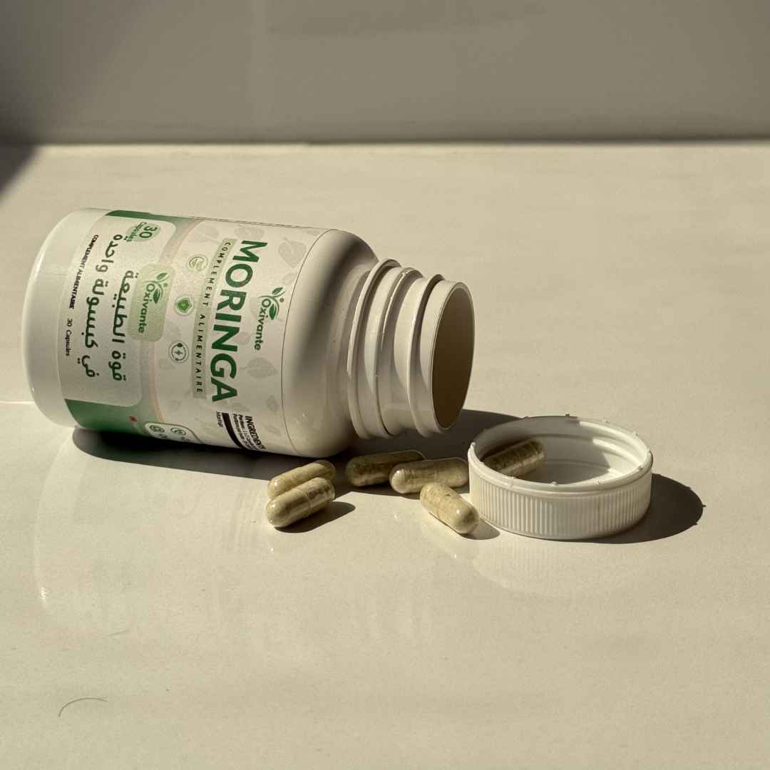 Oxivante Moringa — علبة على جانبها مع كبسولات مسكوبة وظلال طبيعية