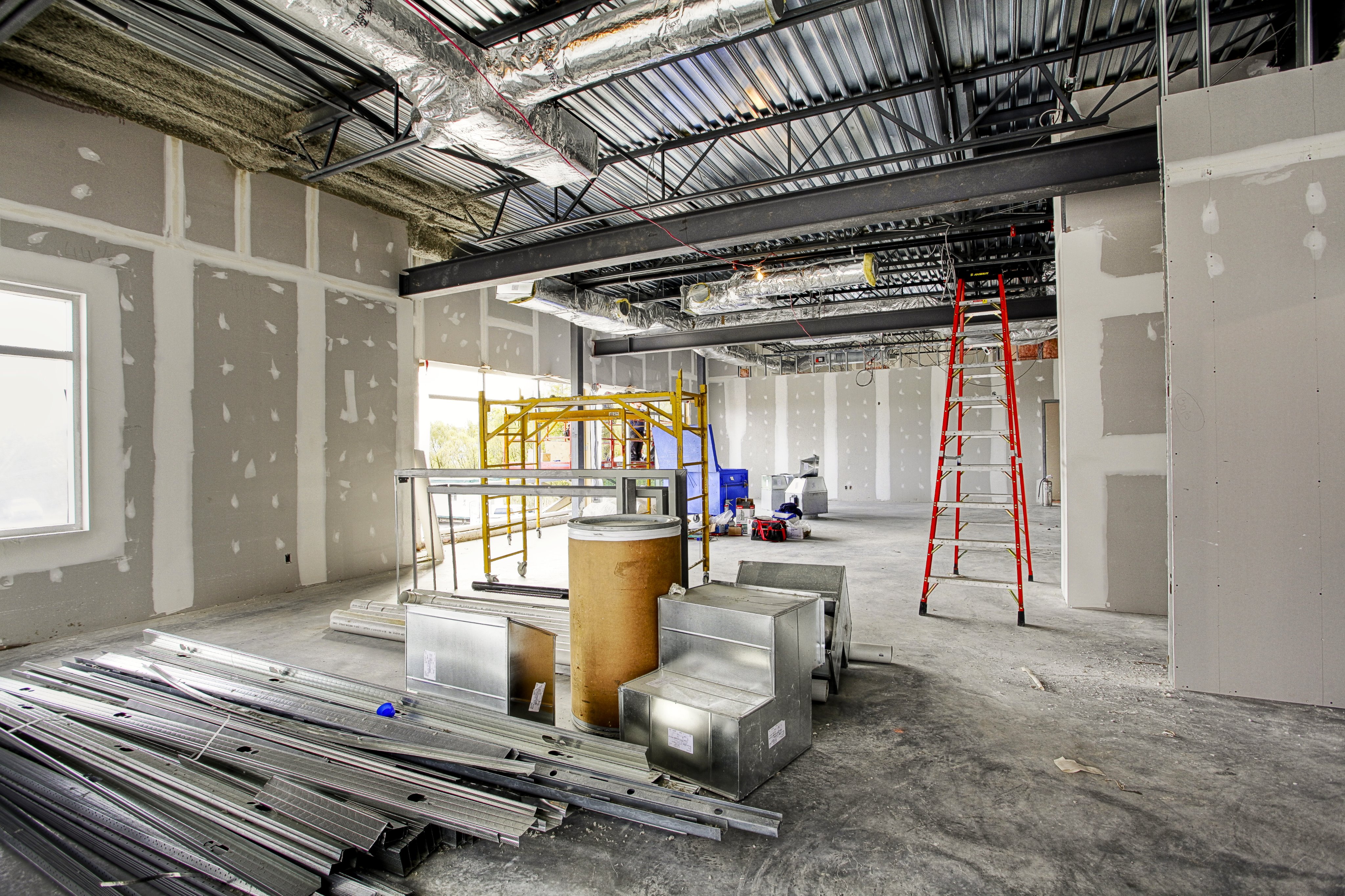 Commercial interior framing with exposed steel beams, HVAC ducts, scaffolding and construction materials
