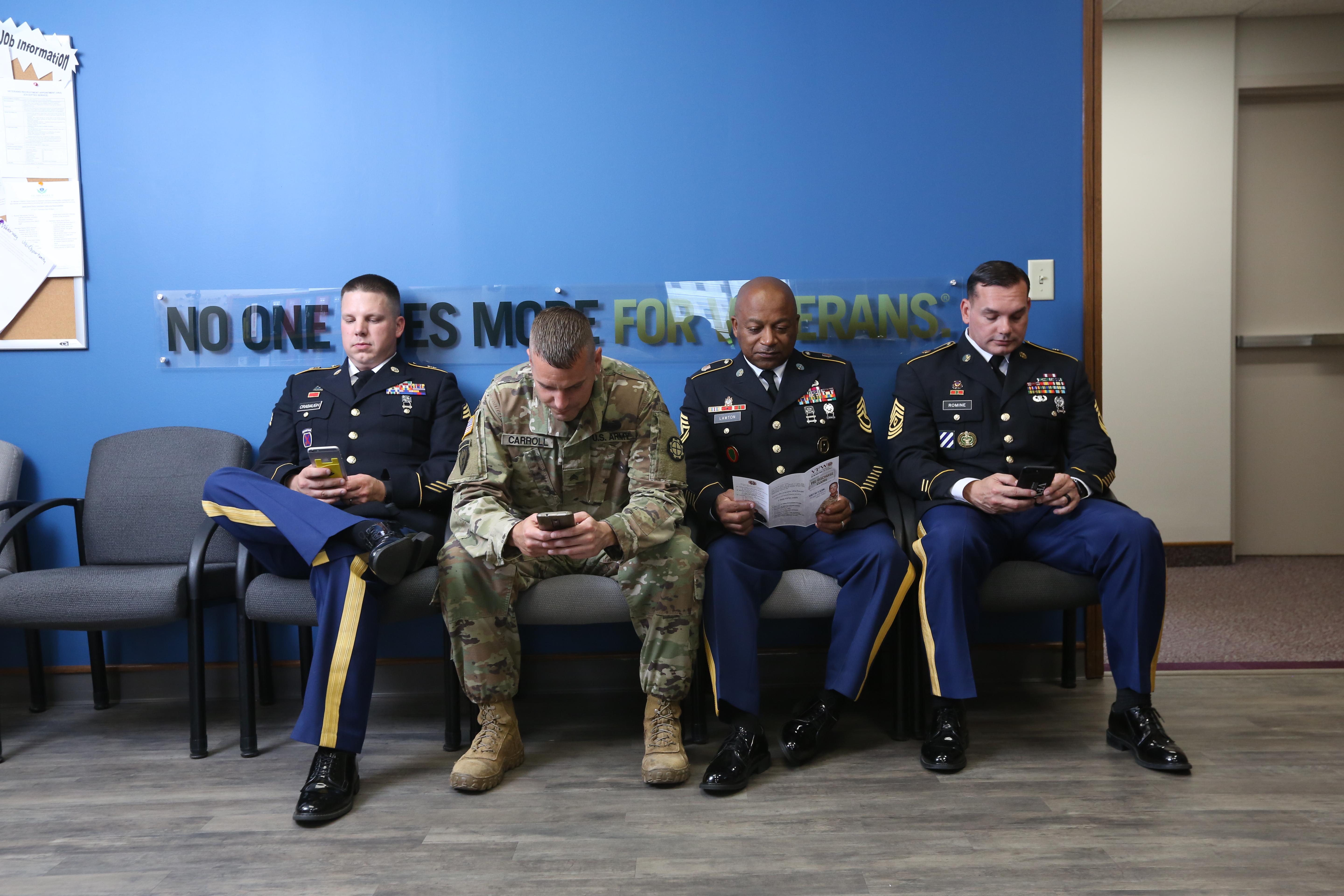 Service members waiting in a VFW office with 'No One Does More For Veterans' sign