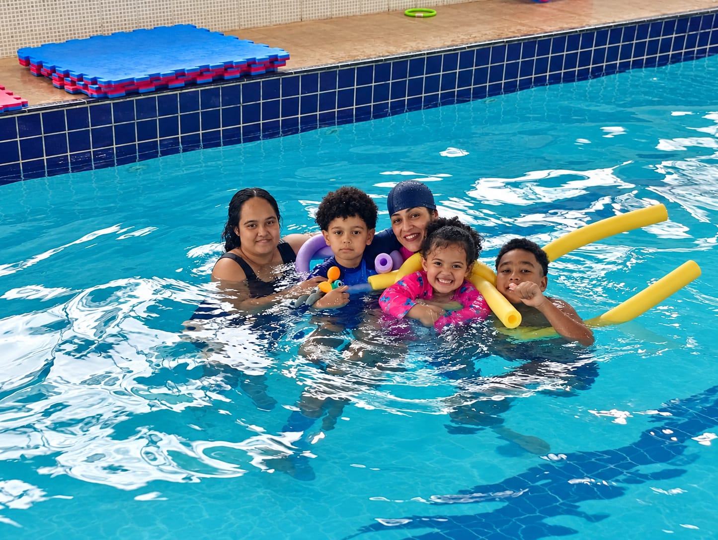 Verônica, mães e alunos reunidos na piscina durante uma atividade do projeto