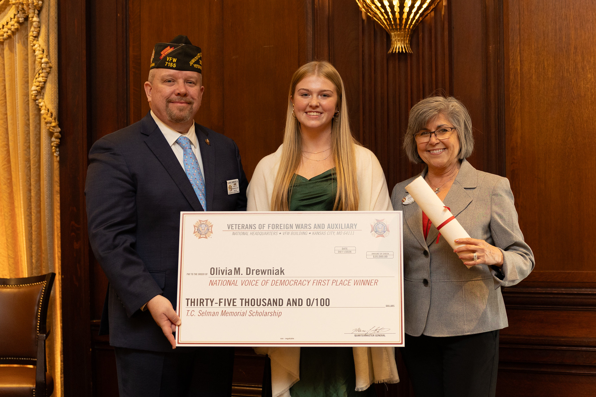 Voice of Democracy national first-place winner Olivia M. Drewniak holding a $35,000 ceremonial scholarship check with two VFW representatives